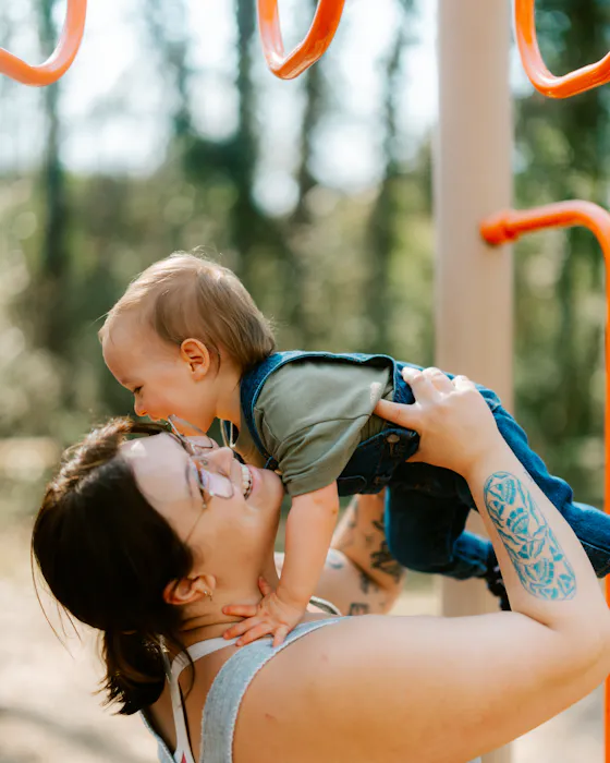A mum lifting her baby high above her head and smiling