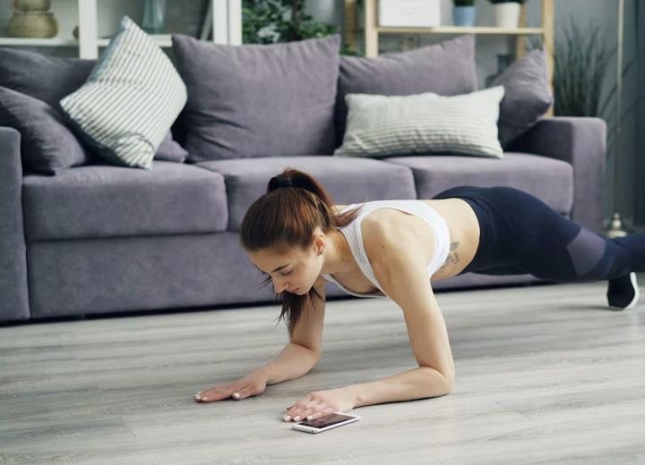 A woman holding a forearm plank on the living-room floor