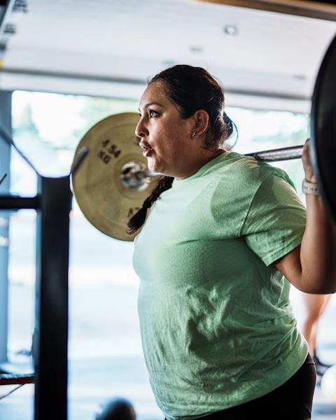 A woman squatting with a barbell across her shoulders