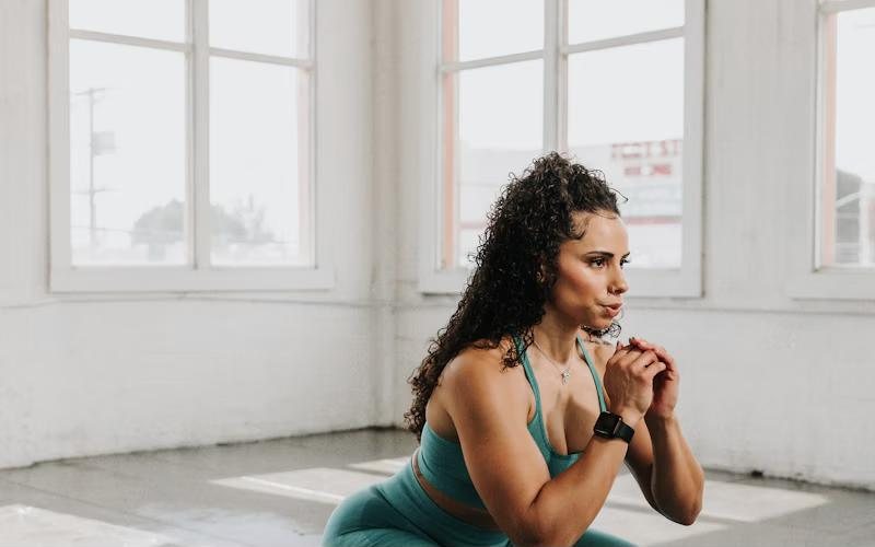 A woman practising a bodyweight squat in a bright studio